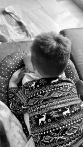 Çun niño de espaldas sujetando la cara de un bebé. Ninguno muestra su cara